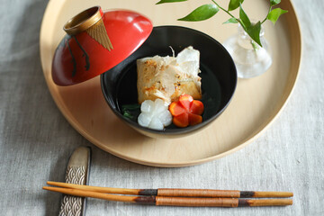 お正月、新年に食べる日本の伝統料理　赤いおわんに入ったお雑煮　飾り切りされたニンジンと大根
