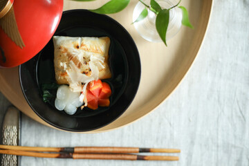 お正月、新年に食べる日本の伝統料理　赤いおわんに入ったお雑煮　飾り切りされたニンジンと大根