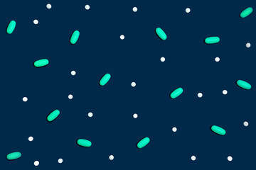 Blue background with many drugs in capsules and tablets of different colors scattered on the surface