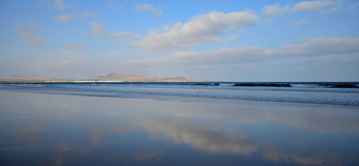 Beautiful panoramic with the reflection of the sky on the seashore, Famara beach, Lanzarote, Canary Islands