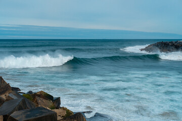 Sea waves and rocks. Seasore. Basque country landscape. Rainy weather. Blue water and sky.