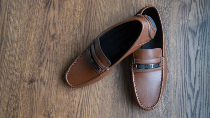 BROWN MOCCASIN SHOES, ON WOODEN FLOOR WITH NATURAL LIGHTING AND SPACE FOR TEXT