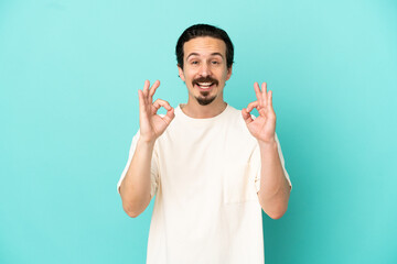 Fototapeta premium Young caucasian man isolated on blue background showing ok sign with two hands