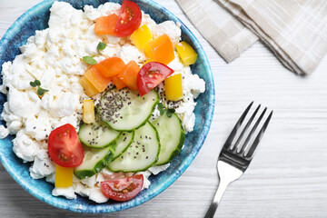 Delicious cottage cheese with vegetables and chia seeds served for breakfast on white wooden table, flat lay