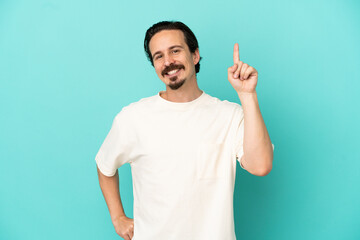 Fototapeta premium Young caucasian man isolated on blue background showing and lifting a finger in sign of the best