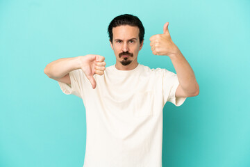 Fototapeta premium Young caucasian man isolated on blue background making good-bad sign. Undecided between yes or not