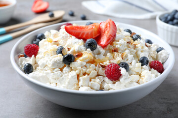 Delicious cottage cheese with fresh berries served for breakfast on light grey table, closeup