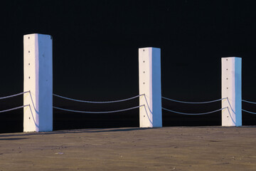 A barrier made with white columns and ropes with a dark night sky background