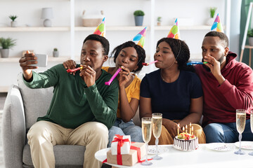 Cheerful group of black friends taking selfie while birthday party