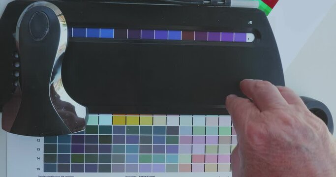 Technician uses a spectrocolorimeter to read patches with various colors for color management related to creating an icc color profile for the printer
