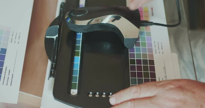 Technician uses a spectrocolorimeter to read patches with various colors for color management related to creating an icc color profile for the printer