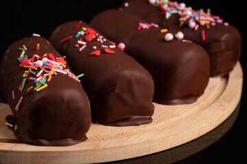 Sweet glazed curds in dark chocolate with strawberry stuffing on black background
