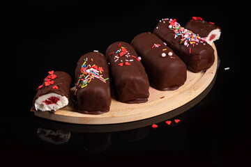 Sweet glazed curds in dark chocolate with strawberry stuffing on black background
