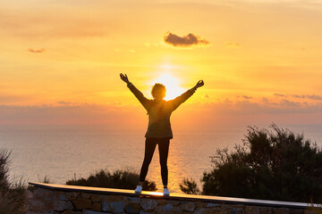 Fototapeta na wymiar Silhouette of a female hiker with open arms as sunrise