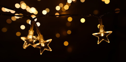 Christmas warm gold garland lights over dark background with glitter overlay