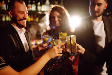 Cheering and drinking cocktails. Group of friends partying in a nightclub and toasting drinks with cocktails. Happy people enjoying winter holiday. Party, celebration, drink, birthday concept.