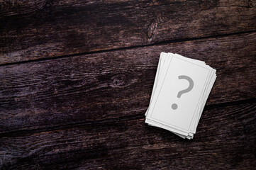 Chance cards, gambling, FAQ or unanswered questions Concept. A stack of playing cards, printed with a question mark, on a rustic wooden background. Table top view, flat lay, copy space.
