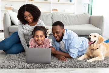 Black family using pc relaxing with dog at home