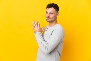 Young caucasian handsome man isolated on yellow background scheming something
