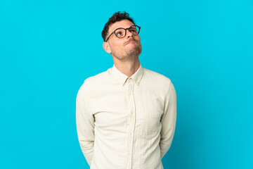 Young caucasian handsome man isolated on blue background and looking up
