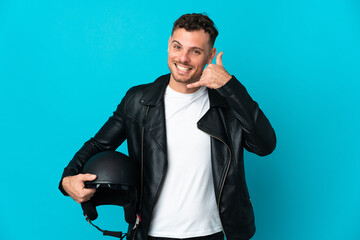 Caucasian man with a motorcycle helmet isolated on blue background making phone gesture. Call me back sign