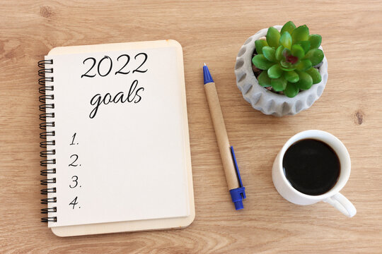 Business concept of top view 2022 goals list with notebook, cup of coffee over wooden desk