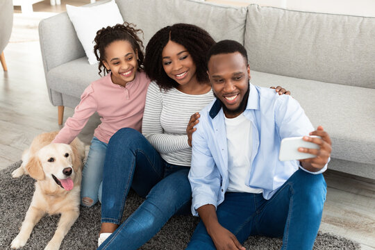 Young black family taking selfie with pet at home