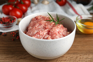 Raw chicken minced meat with rosemary on wooden table, closeup