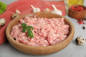 Raw chicken minced meat with basil and quail eggs on grey table, closeup