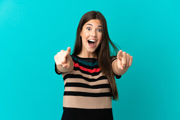 Fototapeta premium Teenager Brazilian girl over isolated blue background surprised and pointing front