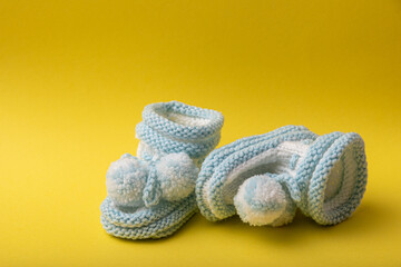 Fototapeta na wymiar homemade knitted shoes for newborn boys on yellow background