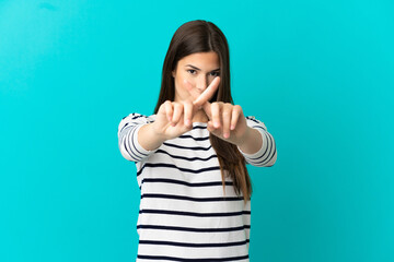 Teenager Brazilian girl over isolated blue background making stop gesture with her hand to stop an act
