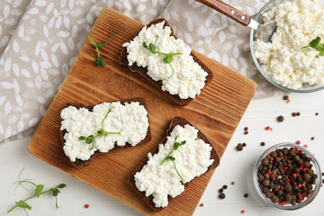 Obraz na płótnie Canvas Bread with cottage cheese and microgreens on white wooden table, flat lay