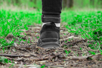 sneakers on the path. girl stands with her foot in the woods. illustration of travel. black shoes on a natural background. hiking concept