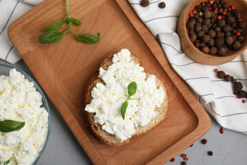 Bread with cottage cheese and basil on grey table, flat lay