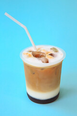 A glass with ice latte coffee cocktail, cold refreshing drink or beverage with ice on blue