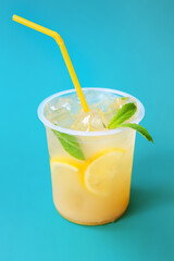 A glass with lemonade or mojito cocktail with lemon and mint, cold refreshing drink or beverage with ice on blue