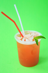 A glass with red lemonade with mint, cold refreshing drink or beverage with ice on green
