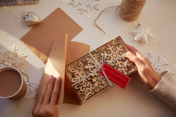 Female hands wrapping Christmas gifts at home. Cozy home. Handmade presents. Christmas preparations