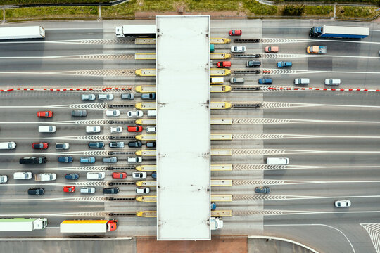 An overhead view of a busy toll road with many cars queuing up to pay the highway toll