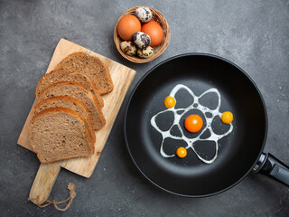 Original fried eggs in the form of an image of an atom from eggs in a frying pan. Chicken and quail...