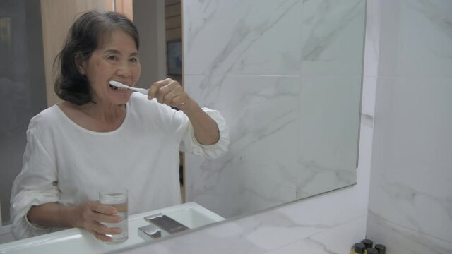 Health concept of 4k Resolution. Asian old woman brushing teeth in the bathroom.