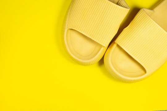Yellow Summer Slippers on the yellow background. Pair of house indoors shoes. Minimalist, creative photo.