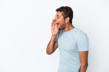 Young handsome Brazilian man isolated on white background shouting with mouth wide open to the side