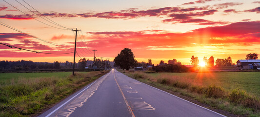 Scenic Road in the countryside and farm lands. Colorful dramatic sunset sky. Located near Abbotsford, East of Vancouver, British Columbia, Canada.