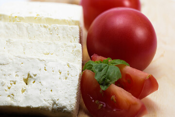 Close up feta cheese, ripe tomatoes, tomato slices, basil	