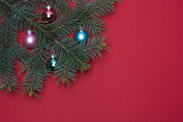 Christmas tree branch with Christmas toys on a red background