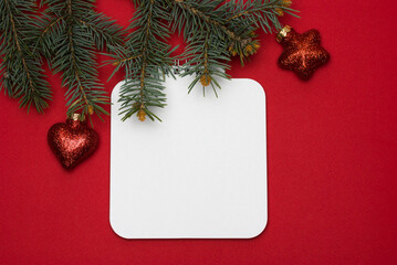 Fototapeta na wymiar Blank sheet of notebook on a twisted spring against the background of a branch of a christmas tree on a red background
