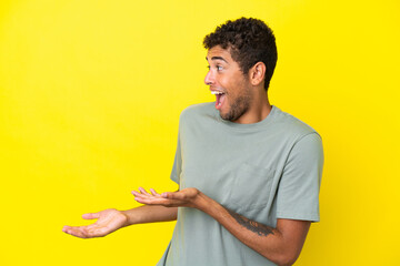Young handsome Brazilian man isolated on yellow background with surprise expression while looking...
