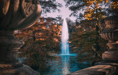 Jardín para relajarse en otoño junto a un lago , fuente de agua en medio del parque, chorro de agua en vertical saliendo del lago en otoño, lugar de relajación y de encuentro de paz  en el parque